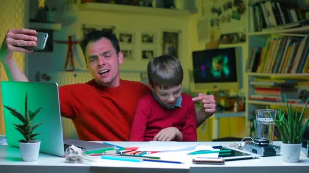 Padre con un niño hace un video blog sentado a la mesa . — Vídeo de stock