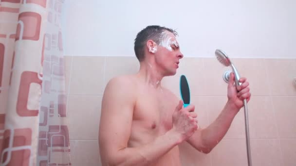Um homem com espuma no rosto canta no banheiro . — Vídeo de Stock