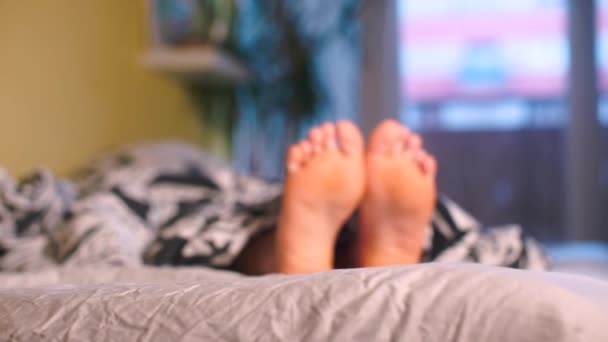 Closeup of the feet of a girl lying in bed in the morning at home. — 비디오