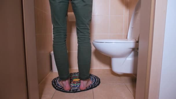 Killen går in i toaletten, tar av sig byxorna och börjar använda smarttelefonen.. — Stockvideo
