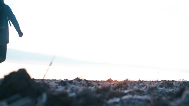 A man in warm clothes and a backpack walks on the ground. — Stock Video