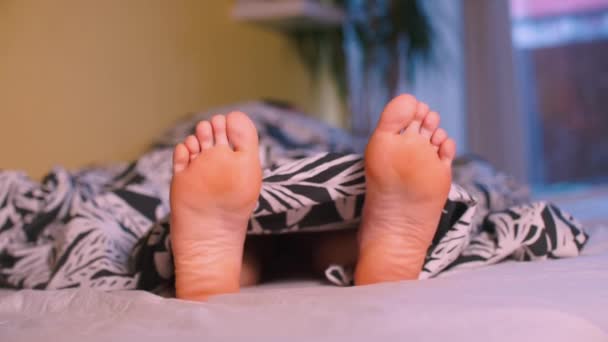 Un gros plan des jambes d'une femme allongée sur un lit . — Video