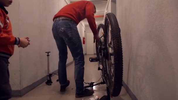 Far och son reparerar en cykel. — Stockvideo