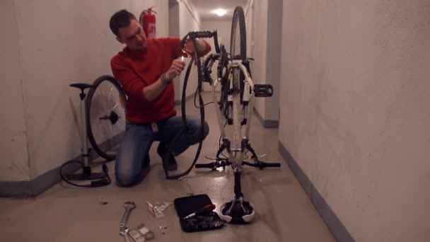 Bir adam bisikletle tekerleği tamir ediyor.. — Stok video