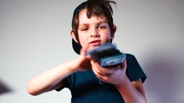 Um garoto alegre em um boné joga dinheiro na câmera . — Vídeo de Stock