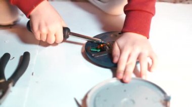 Yakın plan, tornavidalı bir çocuk elektrikli aletini kırıyor..