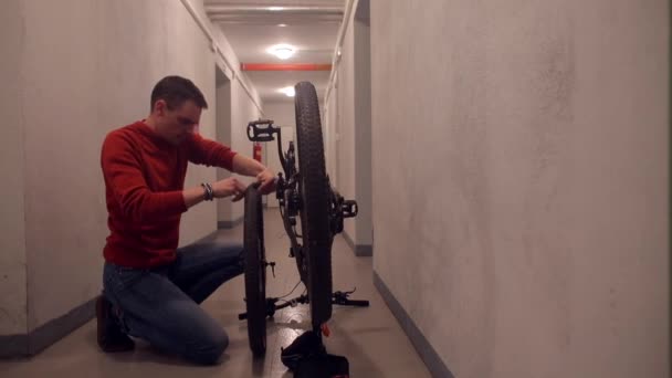 Чоловік розбирає велосипедне колесо і дивиться на камеру . — стокове відео