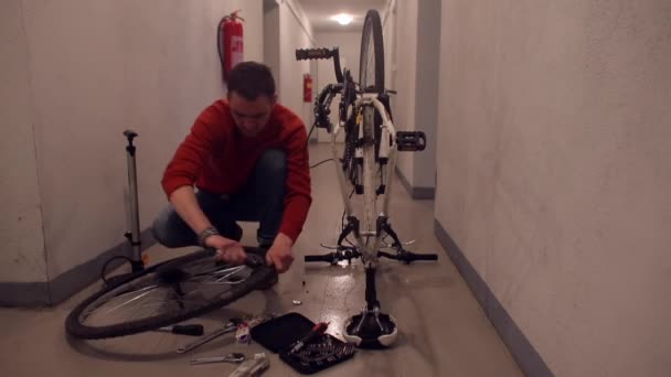 Un hombre desmonta una rueda de bicicleta para sellar un agujero en la goma . — Vídeos de Stock
