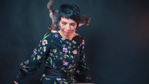 Beautiful woman with gloves in her arms posing with a Devon Rex — Stock Video