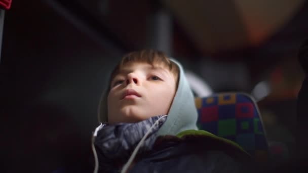 Tonåring i hörlurar åker buss i staden på natten. — Stockvideo