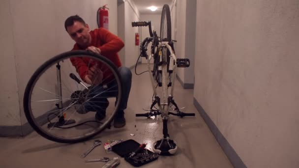 En far reparerar ett hjul i en son cykel i ett garage. — Stockvideo