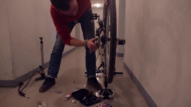 Um homem na garagem desaperta a roda traseira de uma bicicleta . — Vídeo de Stock