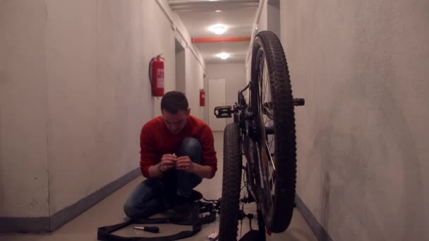 Ein Mechaniker manipuliert mit dem Gummi eines Fahrrads in einer Garage. — Stockvideo