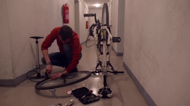 ガレージで自転車の車輪を分解する男. — ストック動画