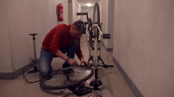 A mechanic in a workshop does manipulations with a bicycle wheel. — Stock Video