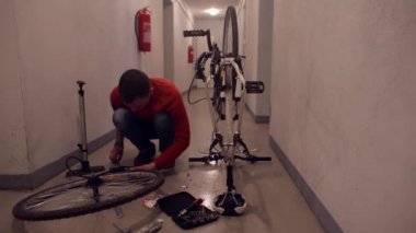 Bir tamirci garaja yerleştirmeden önce bir bisiklet tekerleği monte eder.