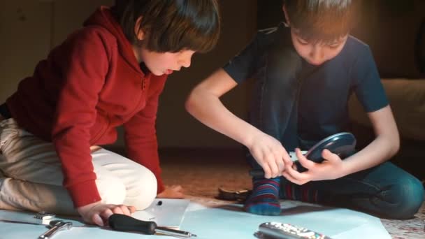 Dos hermanos están jugando con un diseñador de robots en el suelo de la escuela . — Vídeos de Stock