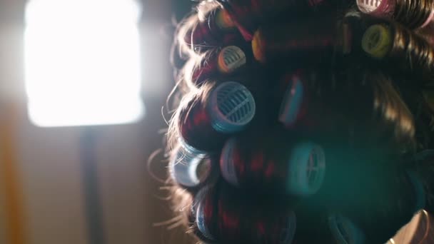 Primer plano de los rulos en el cabello de una mujer cabeza en la luz de fondo . — Vídeos de Stock