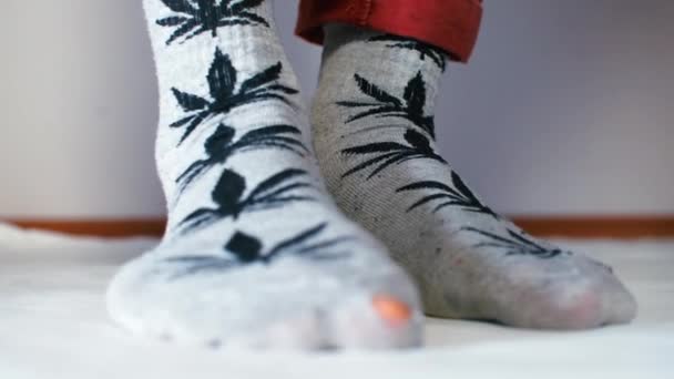 Nahaufnahme männlicher Beine in Socken mit gezogenen Cannabisblättern. — Stockvideo