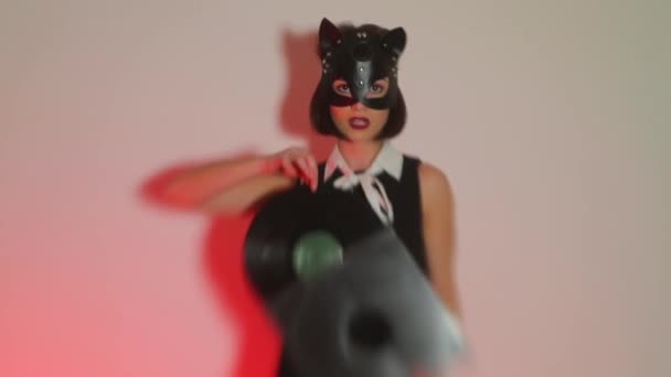 Ragazza DJ in una maschera di gatto tiene in mano un disco in vinile a una festa viziosa . — Video Stock