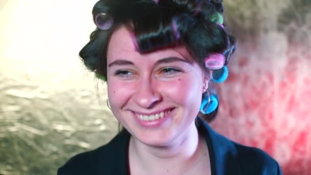 Dona de casa alegre em encrespadores de cabelo posando, endireita o cabelo facial — Vídeo de Stock