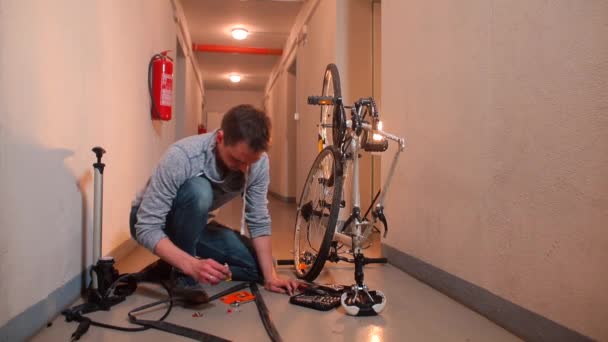 Um colaborador masculino faz um vídeo sobre furar uma roda de bicicleta — Vídeo de Stock