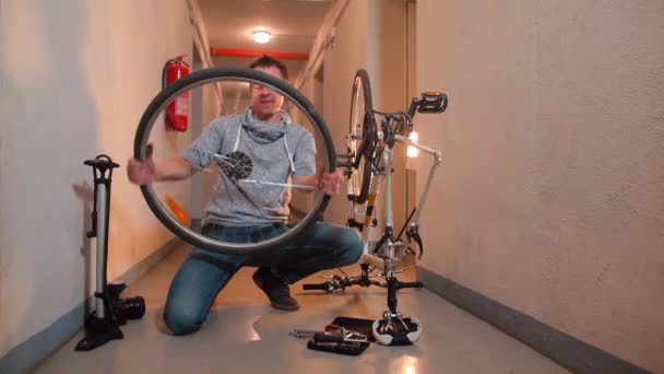 Un uomo sta facendo girare una ruota della bicicletta davanti a lui, ridendo. — Video Stock