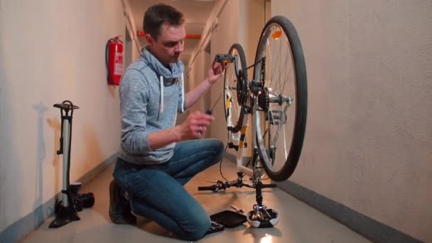Een man dringt aan op een fiets versnellingspook in een werkplaats. — Stockvideo