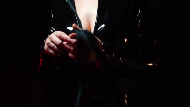 Detailní záběr biče v rukou dominy v latexovém obleku. — Stock video