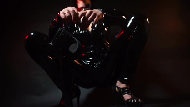 Жінка-домінантка в латексному костюмі тримає наручники в руках . — стокове відео