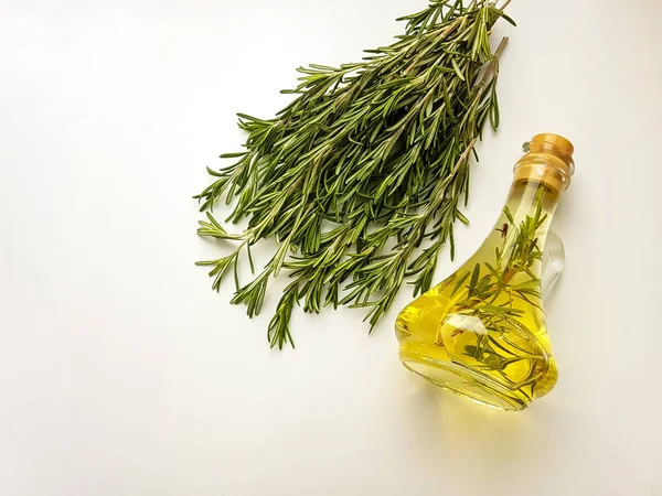 Rosemary fresco fragrante em um fundo branco. Óleo de alecrim em um jarro de vidro . — Fotografia de Stock