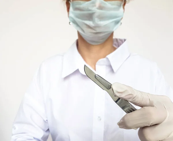 Scalpel in the hand of a surgeon in the operating room on a light background.Medical concept.