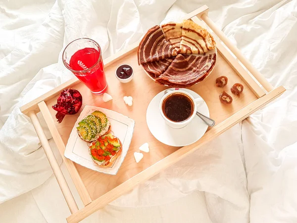 Tasty homemade breakfast in a white bed in the bedroom.