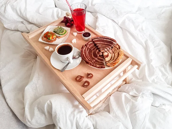 Tasty homemade breakfast in a white bed in the bedroom.