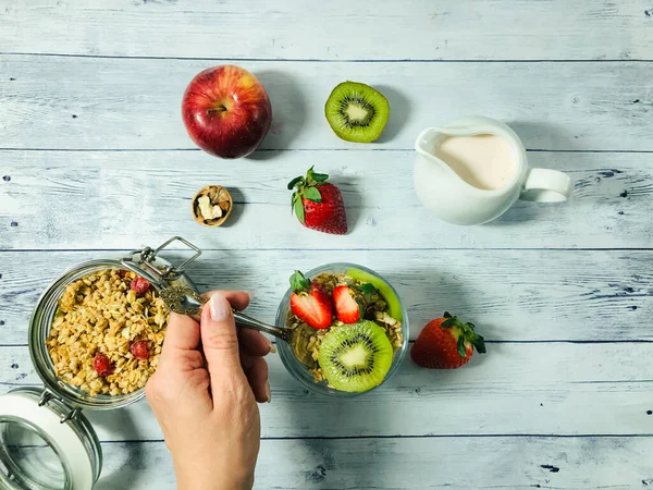 Healthy nutrition. Delicious granola breakfast with yogurt, kiwi, strawberries and nuts on a wooden background. — Stock Photo, Image