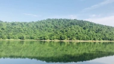 Orman ve dağların arasındaki göl manzarası.