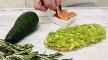 Kız avokado ve somonla bruschetta pişiriyor. Sağlıklı yeme kavramı.