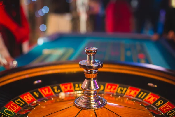 Ein lebendiges Bild aus nächster Nähe von einem bunten Casino-Tisch mit Roulette in Bewegung, mit der Hand eines Croupier und einer Gruppe reicher Glücksspieler — Stockfoto