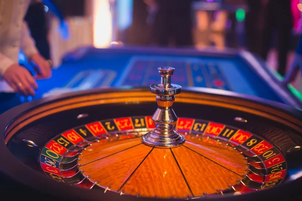 Ένα κοντινό πλάνο εικόνα ζωντανή πίνακας πολύχρωμα καζίνο με ρουλέτα σε κίνηση, με το χέρι του κρουπιέρη, και μια ομάδα των τυχερών παιχνιδιών πλούσια πλούσιοι άνθρωποι — Φωτογραφία Αρχείου