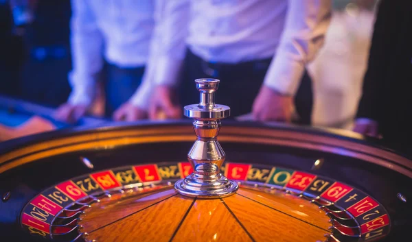 特写的充满活力形象的五彩的赌场表与轮盘赌中运动，与庄家，和一批赌博丰富的有钱人的手 — 图库照片