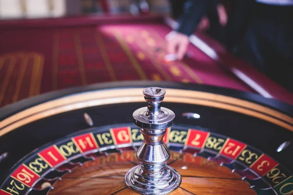 Una imagen vibrante de cerca de la mesa de casino multicolor con la ruleta en movimiento, con la mano de crupier, y un grupo de personas ricas en juegos de azar —  Fotos de Stock