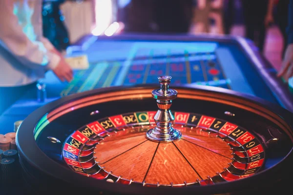 Ένα κοντινό πλάνο εικόνα ζωντανή πίνακας πολύχρωμα καζίνο με ρουλέτα σε κίνηση, με το χέρι του κρουπιέρη, και μια ομάδα των τυχερών παιχνιδιών πλούσια πλούσιοι άνθρωποι — Φωτογραφία Αρχείου