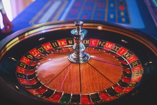 Una imagen vibrante de cerca de la mesa de casino multicolor con la ruleta en movimiento, con la mano de crupier, y un grupo de personas ricas en juegos de azar — Foto de Stock