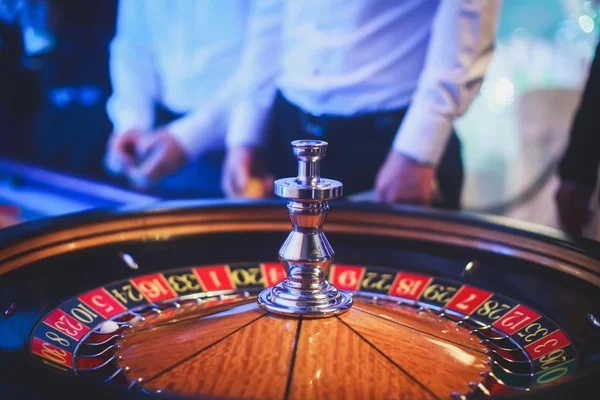 Een close-up levendige beeld van veelkleurige casino tafel met roulette in beweging, met de hand van de croupier, en een groep van het gokken van de rijke rijken — Stockfoto