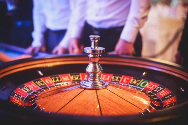 Zbliżenie żywy obraz tabeli wielobarwny kasyno z ruletką w ruchu, ręka krupiera i grupy bogatych ludzi bogatych hazardu — Zdjęcie stockowe