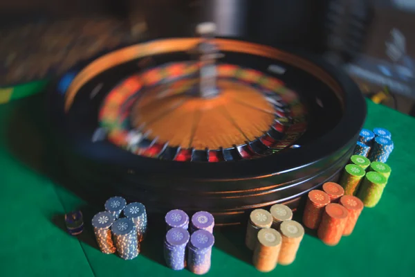 Ein lebendiges Bild aus nächster Nähe von einem bunten Casino-Tisch mit Roulette in Bewegung, mit der Hand eines Croupier und einer Gruppe reicher Glücksspieler — Stockfoto