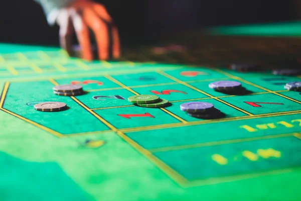 Ein lebendiges Bild aus nächster Nähe von einem bunten Casino-Tisch mit Roulette in Bewegung, mit der Hand eines Croupier und einer Gruppe reicher Glücksspieler — Stockfoto