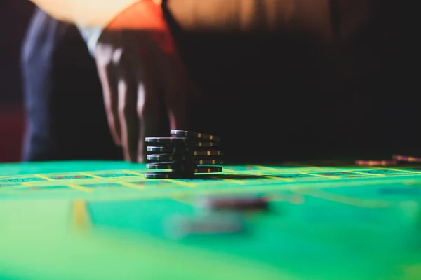 Ein lebendiges Bild aus nächster Nähe von einem bunten Casino-Tisch mit Roulette in Bewegung, mit der Hand eines Croupier und einer Gruppe reicher Glücksspieler — Stockfoto