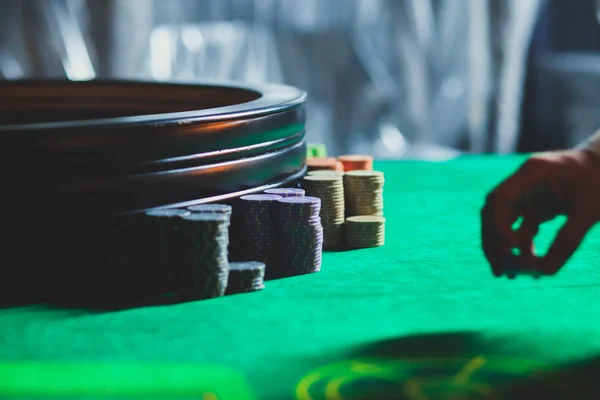 Ein lebendiges Bild aus nächster Nähe von einem bunten Casino-Tisch mit Roulette in Bewegung, mit der Hand eines Croupier und einer Gruppe reicher Glücksspieler — Stockfoto