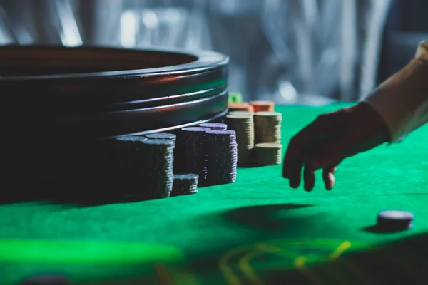 Una imagen vibrante de cerca de la mesa de casino multicolor con la ruleta en movimiento, con la mano de crupier, y un grupo de personas ricas en juegos de azar — Foto de Stock